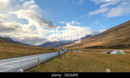 Strada nel nord dell'Islanda che conduce attraverso la valle durante il sole Foto Stock