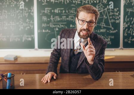 Entusiasta lettore intelligente bearded che comunica con il pubblico durante la lezione di matematica Foto Stock