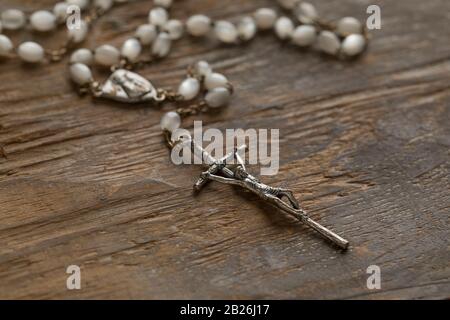 Rosario cattolico a un vecchio tavolo di legno vicino Foto Stock