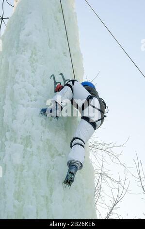 La ragazza sale verso l'alto su una gara di arrampicata su ghiaccio Foto Stock