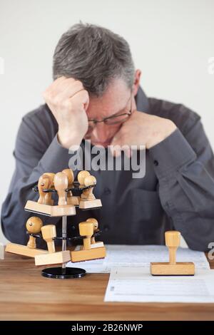 Impiegato frustrato ad una scrivania con i francobolli e i documenti in un ufficio - fuoco sul bollo con copyspace Foto Stock