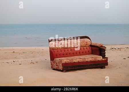 Immagine surreale di mezzo divano rosso sulla spiaggia Foto Stock