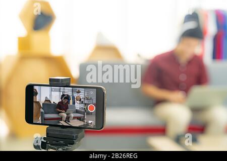 Giovane asiatico maschio giocatore casting e trasmettere il suo gioco di video online con occhiali VR per registrare video vlog dal vivo. Influcencer online e vlo Foto Stock