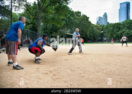 Gioco di softball a Heckscher Ballfields con uomo anziano, Central Park, NYC Foto Stock