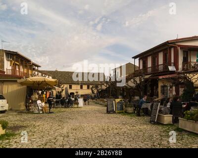 Ammira le acciottolate Demetri Liperti Street Omodos Cyprus, con ristoranti all'aperto che guardano verso il monastero di Santa Croce in questo affascinante antico mou Foto Stock