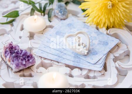 Mazzo con divinazione carte Angelo fatte in casa su un luminoso tavolo bianco, circondato da semi preziosi cristalli di pietre e candele. Fuoco selettivo su cute AN Foto Stock