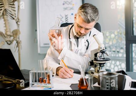 Chimico maschile di scienziati anziani, conduce esperimenti sintetizzando nuovi composti, vaccini, farmaci in moderno laboratorio. Ritratto di scienziato in laboratorio Foto Stock