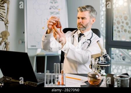 Ricercatore virologo medico senior, analisi di matraccio chimico con nuova sostanza, vaccino, valutazione dei risultati. Il professore ha scoperto un Foto Stock