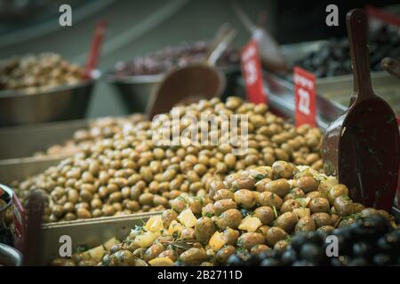 Un mucchio di olive verdi sottaceto vicino ad un cucchiaio. Street food in stile arabo, nel mercato di Mahane Yehuda, Gerusalemme, Israele. Foto Stock