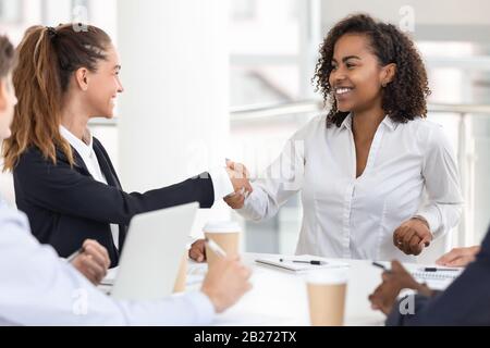 Felice giovane attraente donna nera handshaking con businesswoman bianco Foto Stock