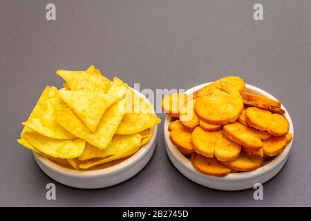 Spuntini salati speziati assortiti. Nachos, cracker. In ciotole di ceramica su uno sfondo di pietra, primo piano Foto Stock