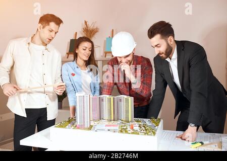 quattro giovani che si divertono in ufficio, esaminando il modello. primo piano foto Foto Stock