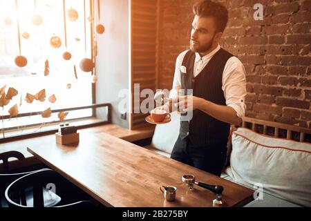 giovane barista professionista con un titolare e una tazza che mostra il workshop, ragazzo che pratica la preparazione dell'espresso sul posto di lavoro. stile di vita, interesse Foto Stock