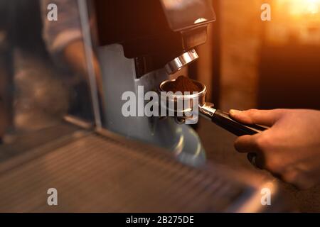 giovane uomo che tiene il portafiltro e controlla la nuova macchina per caffè. primo piano foto vista laterale. attenzione al portafiltro Foto Stock