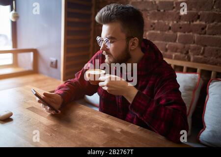 giovane uomo impressionante risolvere i problemi del suo smartphone, primo piano vista laterale foto. gadget, tecnologia, Foto Stock