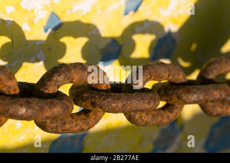 Catena di ferro arrugginita proietta un'ombra su una barca. Foto Stock