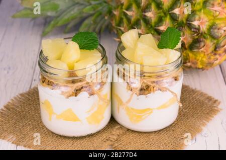 Due vasetti di yogurt all'ananas fatto in casa. Un concetto di dessert leggeri e sani. Foto Stock