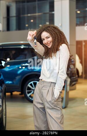 ragazza divertente eccitato con i capelli ondulati lunghi ha comprato una nuova automobile, nuova esperienza, lifestyle, interesse, hobby, fotografia di primo piano, vendita, sconto, acquisto felice dell'automobile Foto Stock