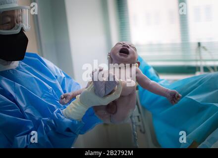 L'ostetrica Wu Dan porta il neonato alla madre Liu Ting nella sala di consegna del Wuhan Maternal and Child Health Hospital di Wuhan, nella provincia centrale cinese di Hubei, 1 marzo 2020. All'inizio della mattinata del 29 febbraio, il volontario Wang Zhen scacciò dalla sua comunità subito dopo aver ricevuto una richiesta di aiuto da una donna incinta che viveva a 30 chilometri di distanza in un'altra comunità a Wuhan. Wang portò la donna incinta e la sua famiglia al Wuhan Maternal and Child Health Hospital, dove la donna partorì in modo sicuro il suo bambino. Il 23 Gennaio, Wang Zhen, A. Foto Stock