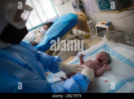 L'ostetrica Wu Dan si prende cura del bambino di Liu Ting nella sala di consegna del Wuhan Maternal and Child Health Hospital di Wuhan, nella provincia Hubei della Cina centrale, il 1° marzo 2020. All'inizio della mattinata del 29 febbraio, il volontario Wang Zhen scacciò dalla sua comunità subito dopo aver ricevuto una richiesta di aiuto da una donna incinta che viveva a 30 chilometri di distanza in un'altra comunità a Wuhan. Wang portò la donna incinta e la sua famiglia al Wuhan Maternal and Child Health Hospital, dove la donna partorì in modo sicuro il suo bambino. Il 23 gennaio, Wang Zhen, un fotoricettore del calcolatore Foto Stock