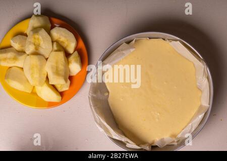 Donna che versa l'impasto per una torta in uno stampo di alluminio imbottito con carta pergamena. Foto Stock