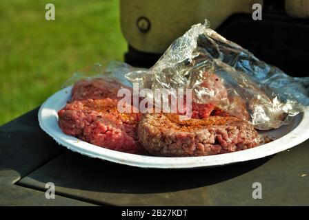 Terra cruda hamburger di manzo polpette pronto essere messo sulla griglia in corrispondenza di una parte del cortile Foto Stock