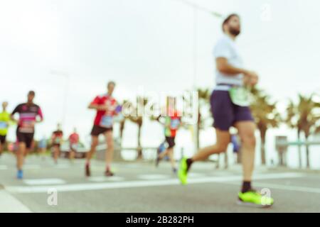 Immagine offuscata delle persone che corrono in una maratona massiccia in una giornata estiva soleggiata. Sano concetto di vita, allenamento e sport. Foto Stock