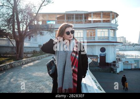 Allegre donne che camminano sulla strada della città godendo del tempo libero nei fine settimana di primavera, donna felice negli occhiali da sole evoca l'aria fresca di mare Foto Stock