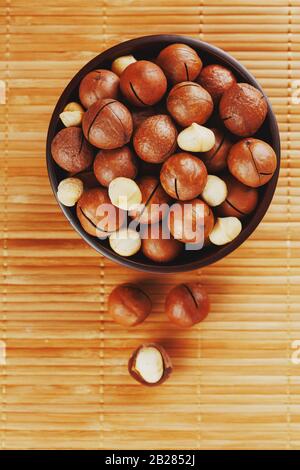 Noce macadamia su tessuto di bambù in una tazza di legno, pelato e non pelato noce, vista dall'alto Foto Stock