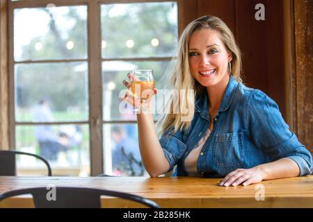 Ritratto di una donna in un taproom bere tap pinte di birra artigianale o sidro, vino Foto Stock