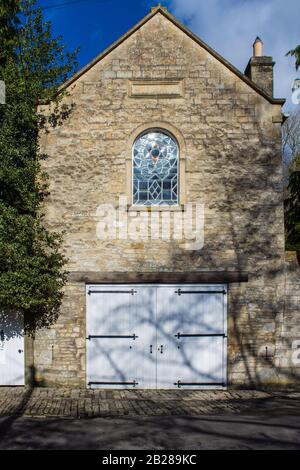 Una casa di pullman convertito con una finestra di vetro colorato sopra porte a carrello con cerniere di ferro lungo in stile fler-de-lis nella frazione di Turleigh in Foto Stock