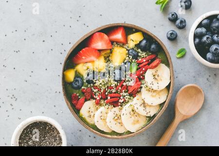 Frullato superfood crudo in ciotola di cocco con superfood condimenti semi di canapa, semi di chia, frutti di bosco di goji banana di mango mirtillo e fragola Foto Stock