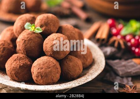 Mucchio di tartufi di cioccolato laminati in polvere di cacao su piastra, vista sul primo piano. Dolci caramelle al cioccolato tartufi fatti in casa Foto Stock