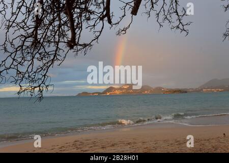 Bell'arcobaleno e rami che incorniciano la foto in un giorno in cui il cielo è stato coperto a Vigie Beach in tropicale Santa Lucia Foto Stock