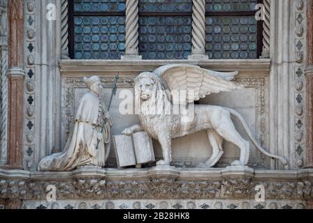 Leone alato e un sacerdote con una Bibbia in Piazza San Marco, Palazzo dei Dogi. Frammento di ingresso di Palazzo Ducale. Il Leone è il simbolo di Venezia. Foto Stock