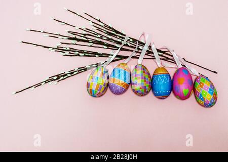 Le colorate uova di Pasqua di carta si trovano su uno sfondo rosa. Concetto di Pasqua Foto Stock