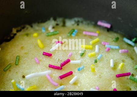 Primo piano di sprinkler dolci multicolore su una torta alla vaniglia Foto Stock