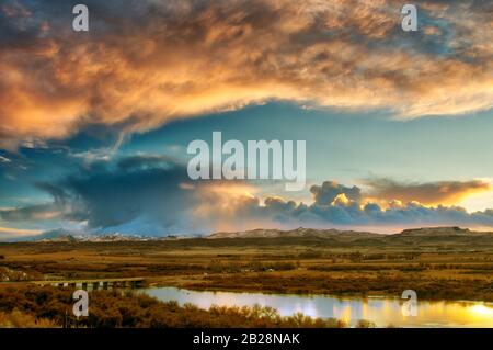 Tramonto scuro e fading sole illuminato nuvola coperta cielo in tarda serata guardando sopra il fiume serpente con la montagna Owyhee Rage in lontananza a Ida Foto Stock