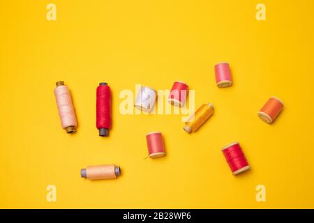 Vista dall'alto di rocchetti multicolori o accessori per cucire su sfondo giallo. Foto Stock