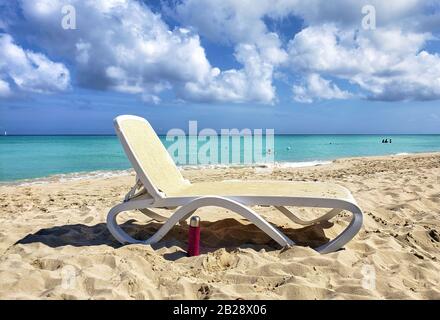 Un lettino vuoto e solitario in una giornata di sole sulla spiaggia cubana. Foto Stock