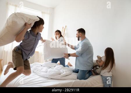 Famiglia giovane con i capretti impegnati nella lotta del cuscino nel paese Foto Stock