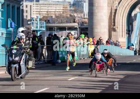 Kenenisa Bekele Racing nella mezza maratona Vitality Big Half attraversa Tower Bridge, Londra, Regno Unito. Correre oltre gli atleti in sedia a rotelle, dietro la bici della tv Foto Stock