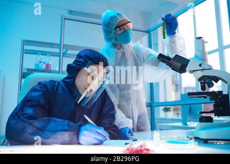 Ritratto di due scienziati che indossano attrezzature a rischio biologico mentre si lavora alla ricerca in laboratorio biologico Foto Stock