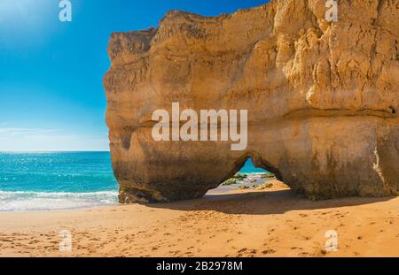 Bella spiaggia di sabbia con scogliera gigante con arco vicino Portimao nella regione dell'Algarve, Portogallo, Europa in giornata di sole Foto Stock