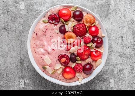 ciotola per frullato o bella crema di banane e frutti di bosco surgelati con frutti di bosco freschi, noci e semi. colazione sana. vista dall'alto Foto Stock