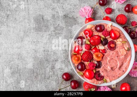 ciotola per frullato o bella crema di banane e frutti di bosco surgelati con frutti di bosco freschi, noci e semi. colazione sana. vista dall'alto con spazio per le copie Foto Stock