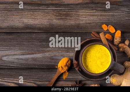 Latte d'oro o latte curcuma fatto con curcuma, anice stellato, zenzero e cannella su rustico tavolo in legno. Vista dall'alto con spazio copia. Bevanda sana. Foto Stock