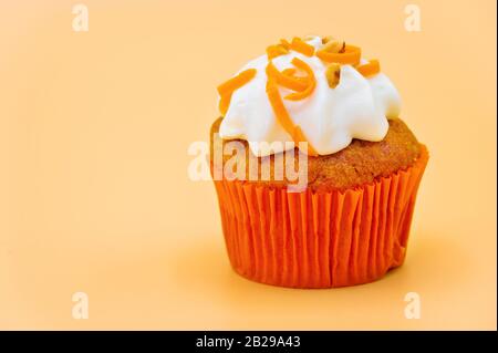 Delizioso cupcake su sfondo color pastello arancione. Foto Stock