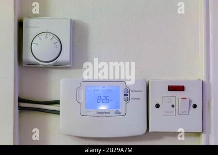 Montato su una parete, un termostato Honeywell impostato a venti gradi, un timer di riscaldamento centrale e un interruttore di interruzione elettrica. Foto Stock
