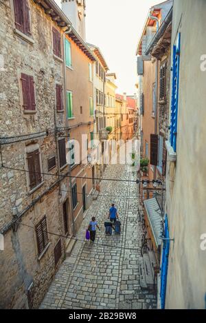 Due turisti hanno impaccato per arrivare o uscire dalla città vecchia di Rovigno attraverso la strada stretta durante mezzogiorno catturato in un colpo verticale Foto Stock